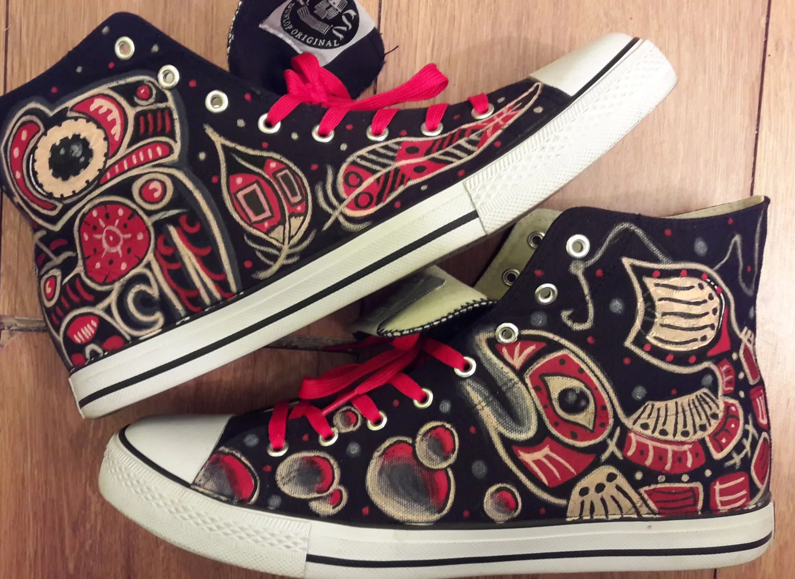 High-top sneakers hand-painted with red and black Pacific Northwest style designs