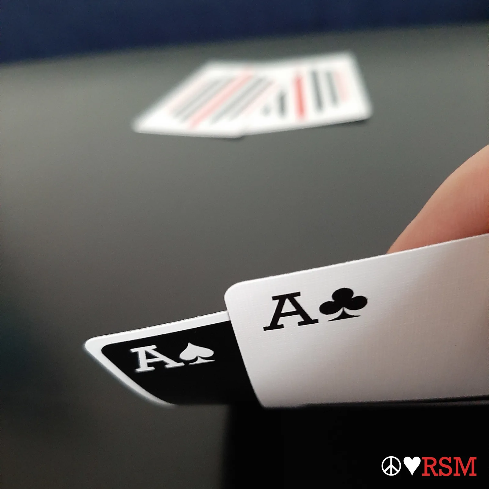 Pinstripe ace of spades and ace of clubs held between fingers